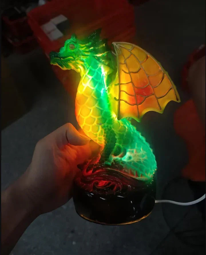 Hand holding a glowing dragon-shaped lamp with vivid green and yellow colors, textured surface.