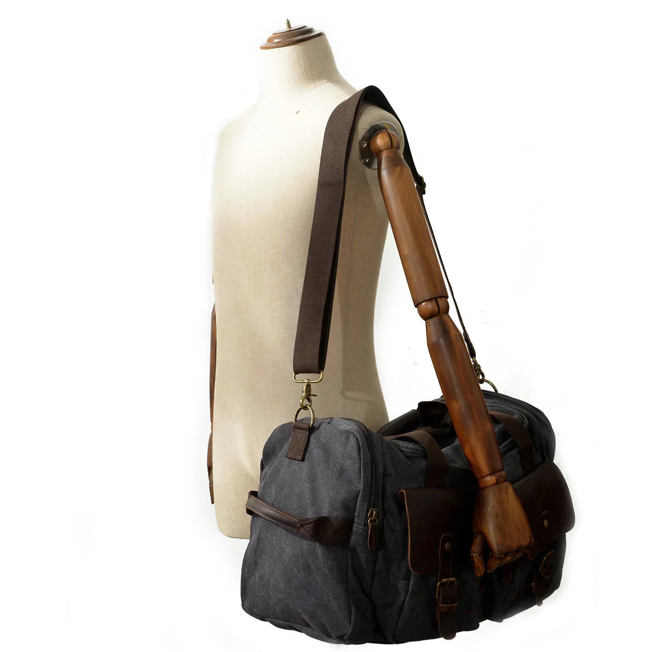 Grey canvas and brown leather duffle bag with adjustable shoulder strap on mannequin