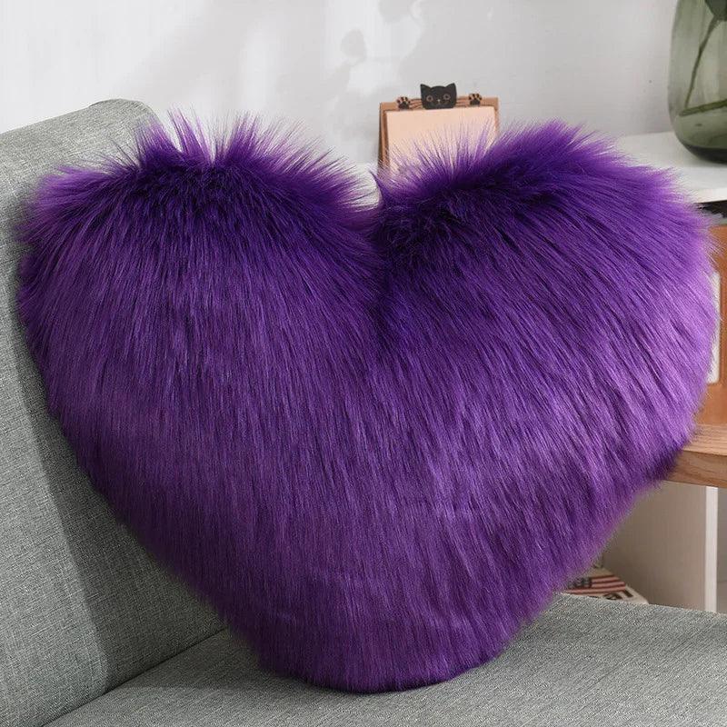 Plush heart-shaped pillow with long purple faux fur on a gray sofa