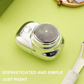 Compact silver electric shaver with circular foil head on light green background