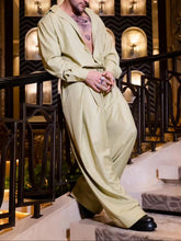 Man wearing light yellow oversized wide-leg pants and an open-collar matching shirt in satin, relaxed fit, indoors
