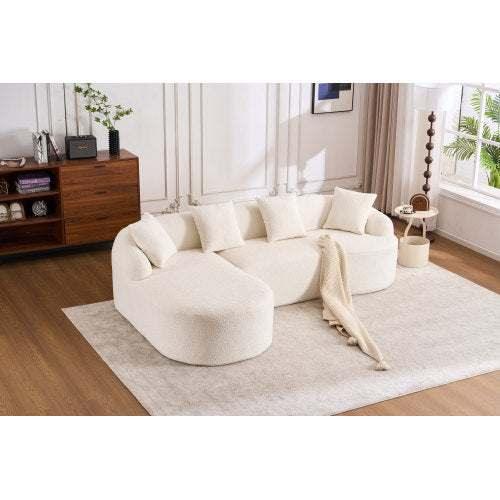 Modern living room with a curved ivory boucle sofa, neutral throw blanket, and accent pillows