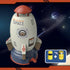 Toy rocket-shaped sprinkler in gray and red plastic with space-themed design and included yellow hose connectors