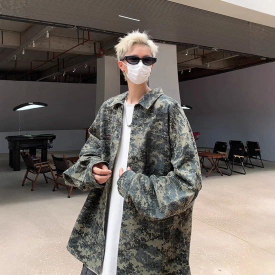 Man wearing oversized camouflage jacket, white t-shirt, streetwear style, relaxed fit.