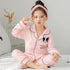 Girl in light pink long-sleeve cotton pajamas with black trim and cartoon dog patch, relaxed fit