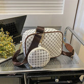 Patterned crossbody bag set with brown accents and wide strap on metal cart