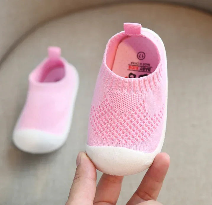 Pink knit slip-on baby shoes with white rubber soles and breathable mesh design