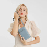 Woman in cream puff sleeve dress holding light blue faux leather crossbody bag