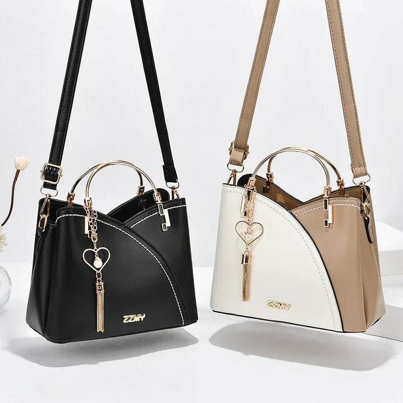 Two modern handbags in black and beige faux leather with gold metal handles and heart tassel charms