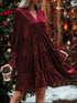 Woman wearing a burgundy velvet long sleeve tiered mini dress, relaxed fit, festive background