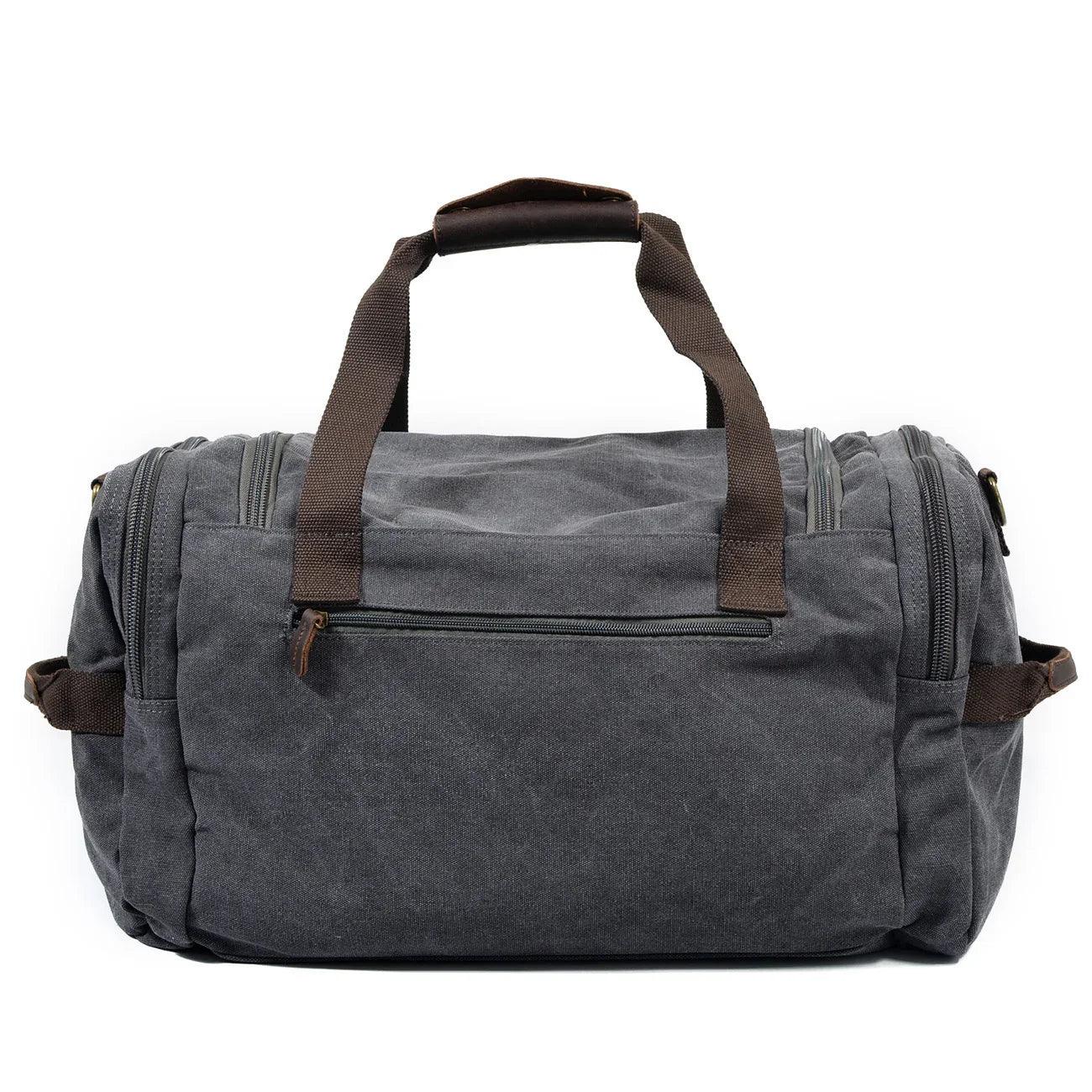 Gray canvas duffel bag with brown handles and exterior zipper pockets, casual fit