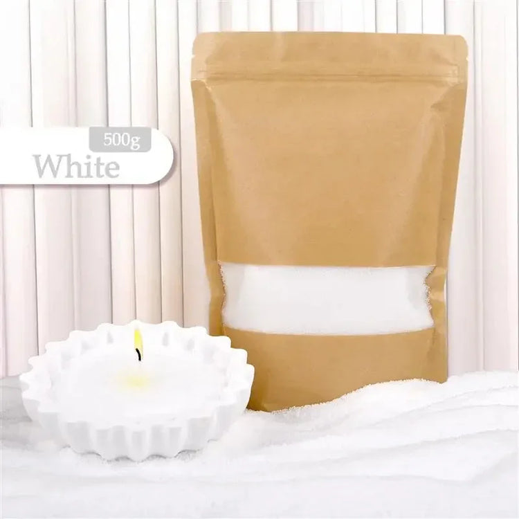 White candle wax flakes in kraft pouch with a lit white candle in a fluted holder