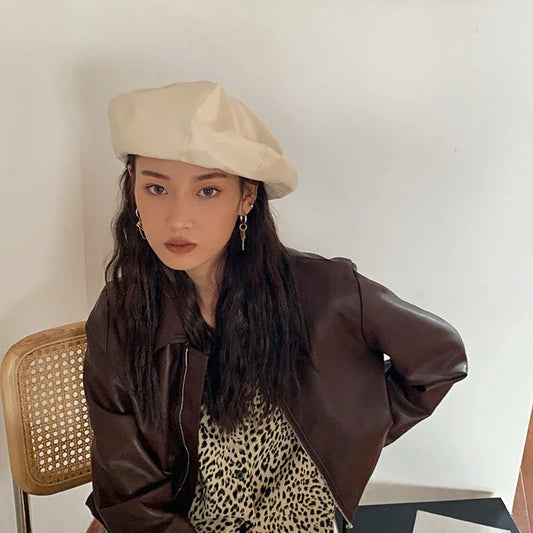 Woman in cream beret, dark brown faux leather jacket, and leopard print top, relaxed fit