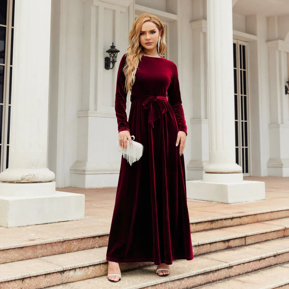 Woman wearing a burgundy velvet long-sleeve maxi dress with a tied waist, elegant fit