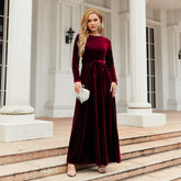 Woman wearing a burgundy velvet long-sleeve maxi dress with a tied waist, elegant fit