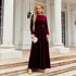 Woman wearing a burgundy velvet long-sleeve maxi dress with a tied waist, elegant fit
