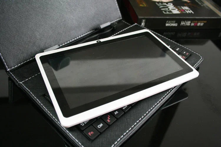 White tablet with black bezel on faux leather keyboard case, tech accessory on desk