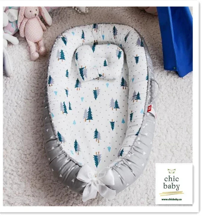 Soft baby nest with white and grey fabric, forest tree pattern, matching pillow, cozy fit.
