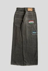 Wide-leg black denim jeans with contrast stitching and colorful embroidered patches on back pockets.