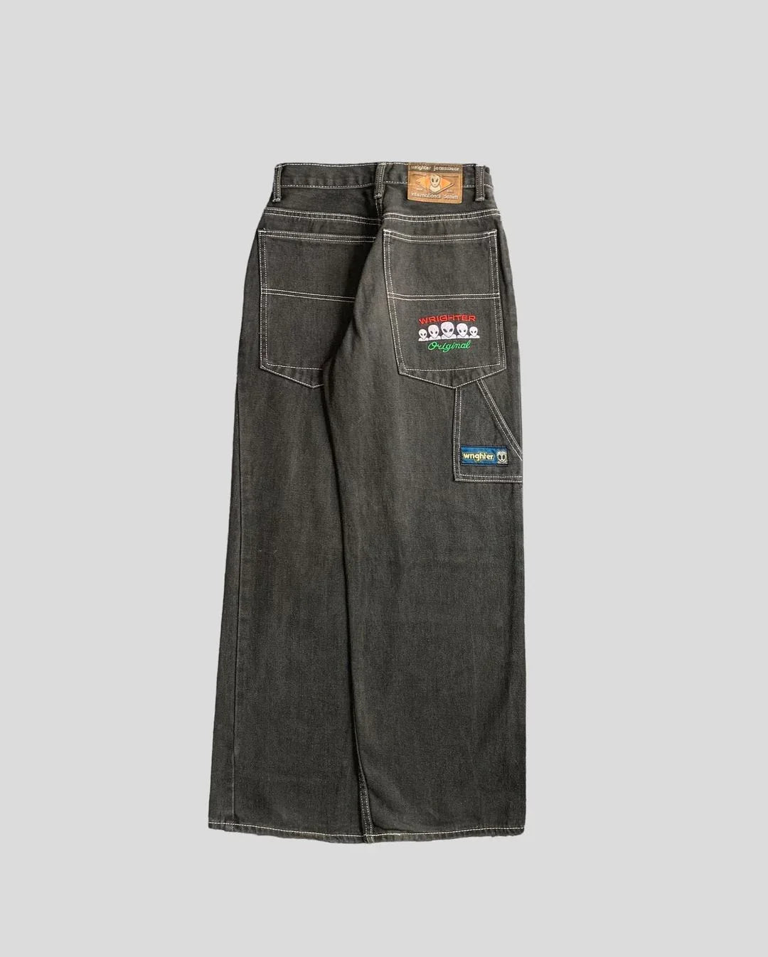 Wide-leg dark denim jeans with white stitching, large patch pockets, and playful embroidered patches on the back.