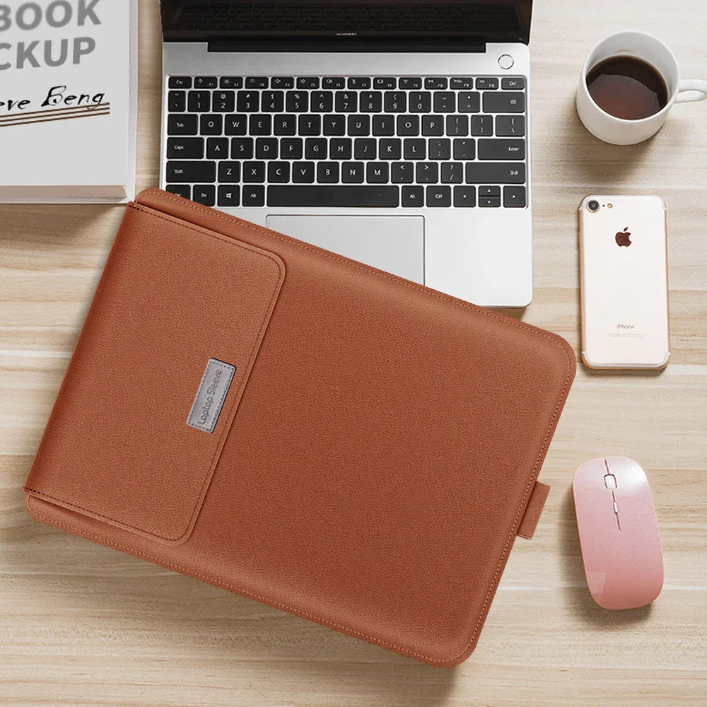 Brown leather laptop sleeve with slim fit on wooden desk beside laptop, coffee, and phone.