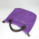 Purple canvas tote bag with brown leather handles and a front zipper pocket, minimalist style