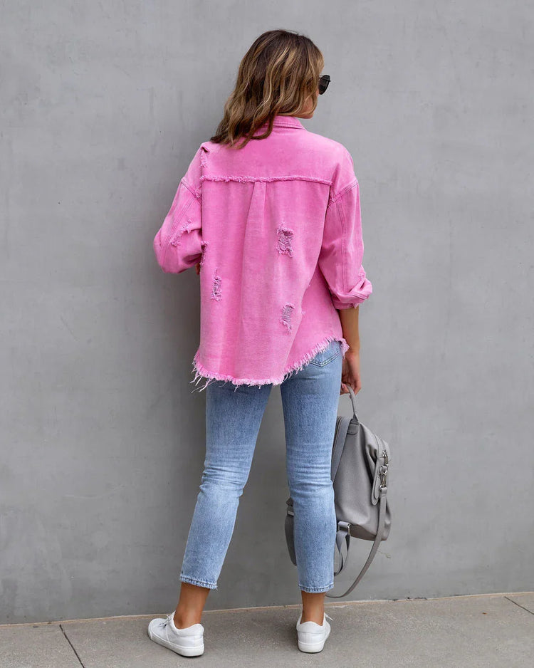 Woman wearing oversized distressed pink denim jacket, light blue skinny jeans, and white sneakers.
