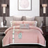 Pink and grey floral bedding set with embroidered patterns on a modern bed