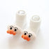 White ribbed baby socks with plush cartoon faces and orange pom-pom noses, soft material