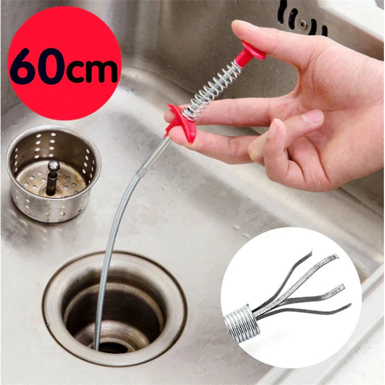 Flexible metal drain clog remover tool with red handle being used in a kitchen sink.