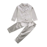 Silver satin pajama set with long sleeves, button front, chest pocket, and relaxed fit pants