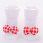 White ribbed baby socks with red and white checkered bow accents, soft cotton material