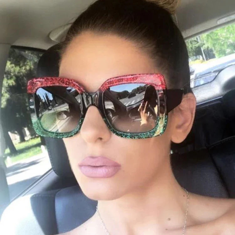 Woman wearing oversized square sunglasses with red and green glitter frames, driving in car