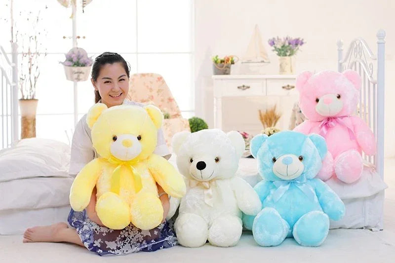 Woman sitting with large plush teddy bears in pastel yellow, white, blue, and pink