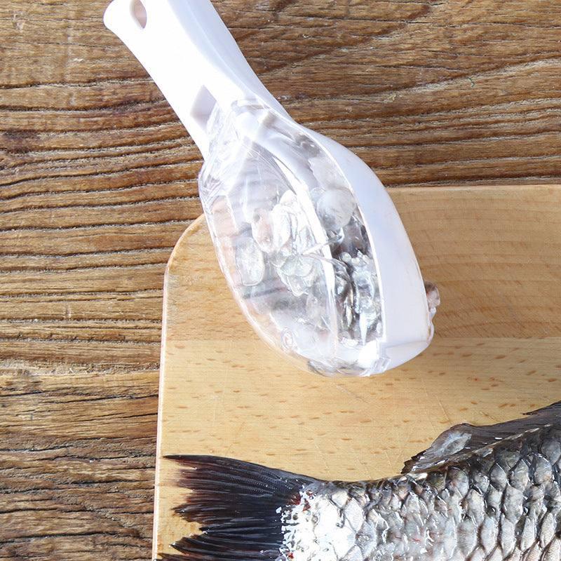 Handheld white fish scaler tool removing scales from fish on wooden cutting board
