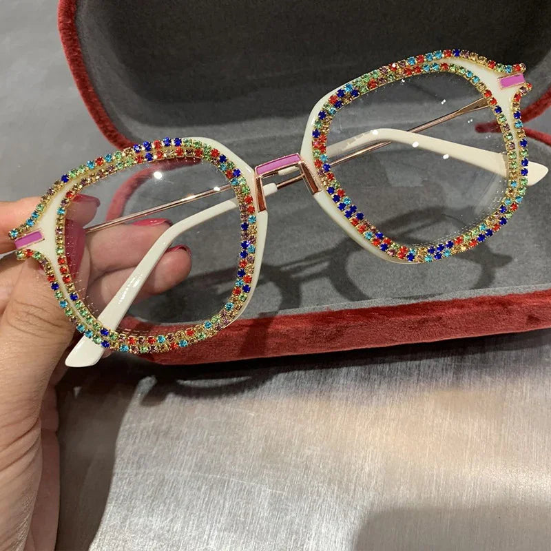 White square-frame glasses with colorful rhinestone accents, held in a velvet case.