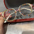 White square-frame glasses with colorful rhinestone accents, held in a velvet case.