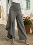Woman wearing high-waisted gray denim wide-leg pants with asymmetric buttoned overlay and silver heels