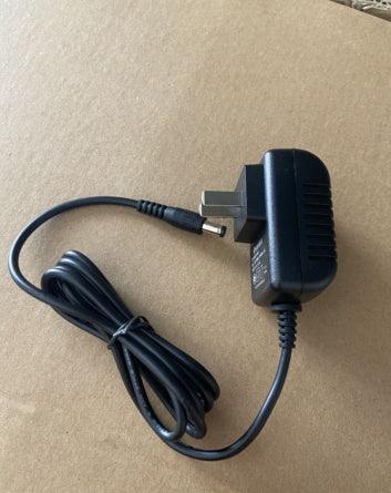 Black wall plug power adapter with cable and barrel connector on a brown background