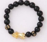 Black bead bracelet with gold-tone charm and engraved bead details, stretch fit.