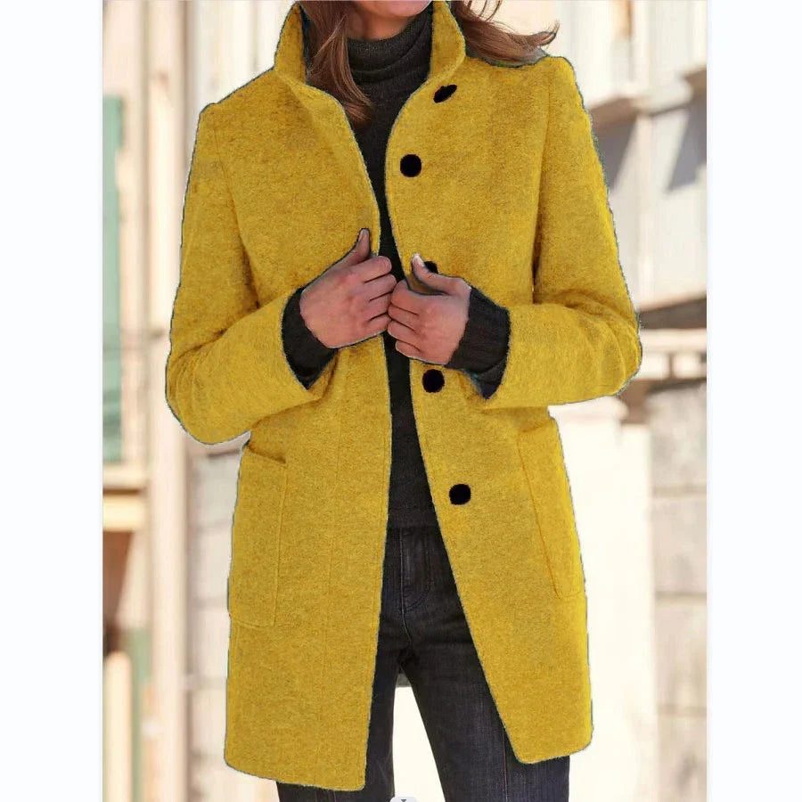 Woman wearing a yellow wool coat with black buttons, straight fit, layered over a dark sweater.