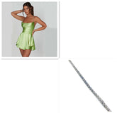 Woman in light green satin mini dress with flared skirt and thin straps, paired with a silver rhinestone bracelet.