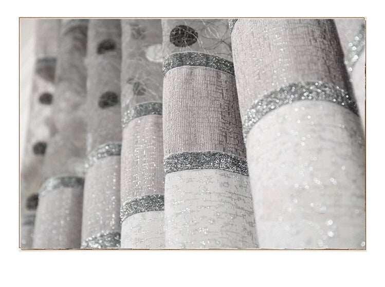 Close-up of light beige curtains with silver glitter accents and textured fabric.