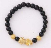 Black beaded bracelet with gold accents and a gold charm, modern streetwear accessory