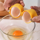 Egg cracking tool with yellow silicone handles neatly splitting an egg over a glass bowl