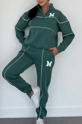 Woman wearing green oversized tracksuit set with white piping, quarter zip top, relaxed fit pants.