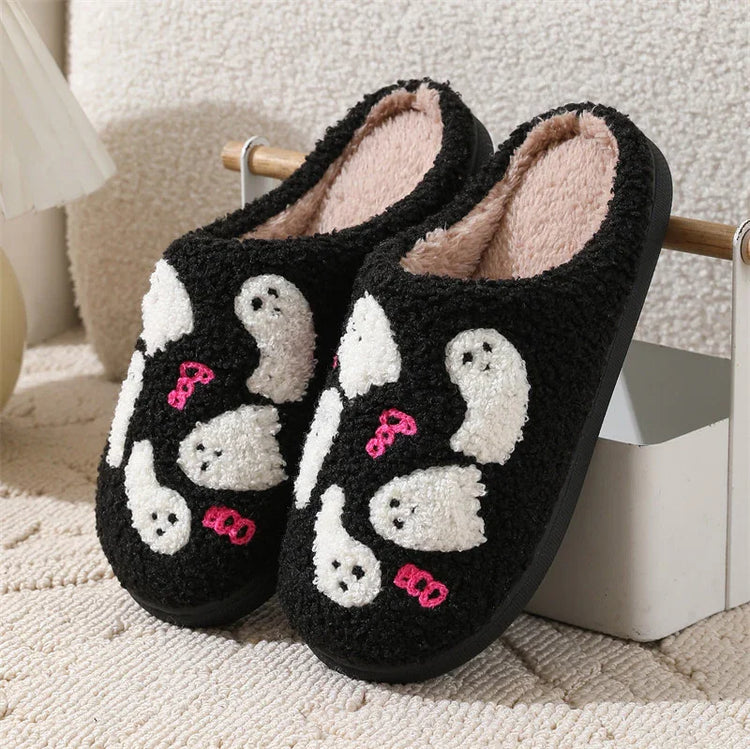 Black fuzzy slippers with white ghost pattern and pink accents, cozy indoor footwear