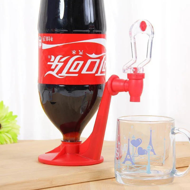 Plastic soda dispenser with red base holding an upside-down bottle next to a glass cup