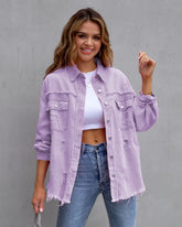 Woman wearing oversized light purple distressed denim jacket, white crop top, and blue jeans