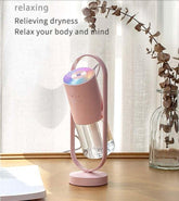 Pink portable humidifier with rainbow LED light, modern design, placed on a wooden table.